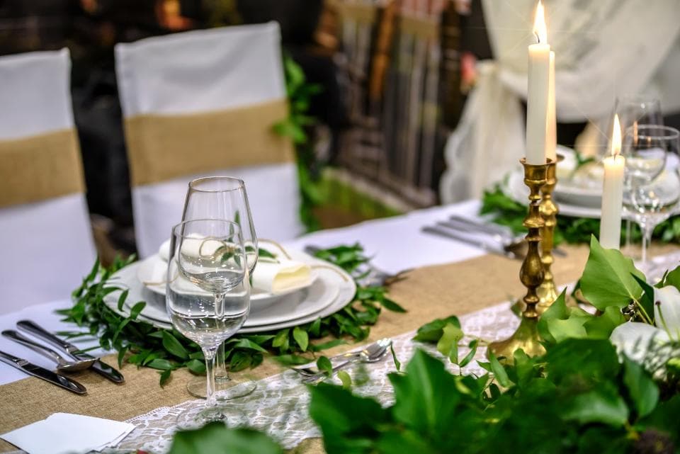 A long table set with candles, glassware and fresh greenery