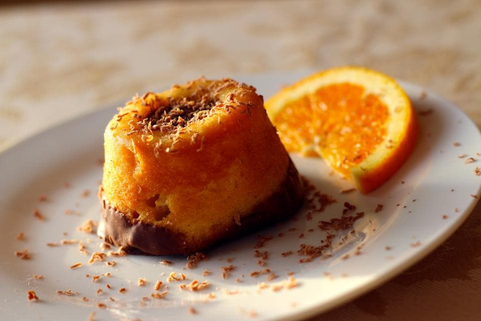 A slice of orange cake with a wedge of fresh orange