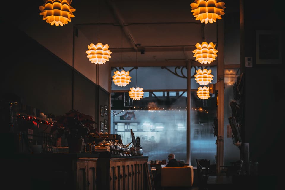 The dining room at dusk, warm pendant lamps glowing over the bar