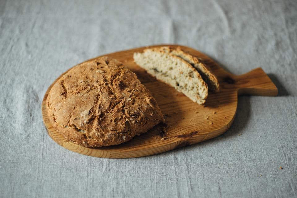 A sourdough loaf on a wooden board, two slices cut